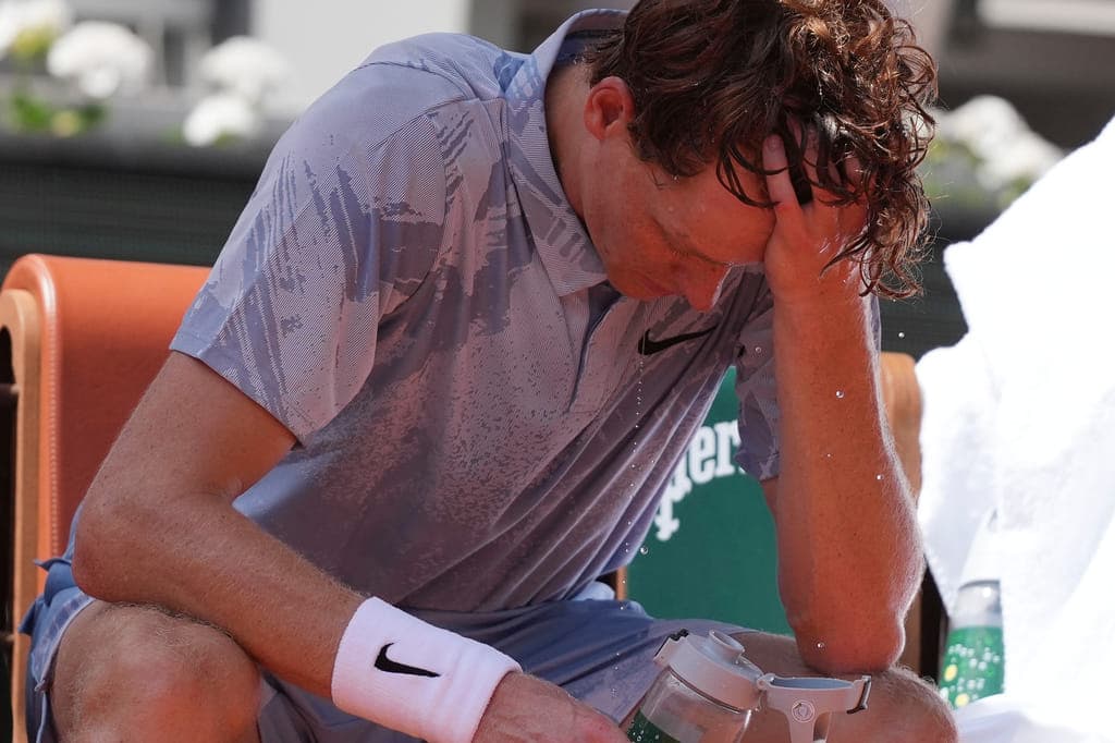 Jannik Sinner playing at the French Open, struggling with heat exhaustion during the match.