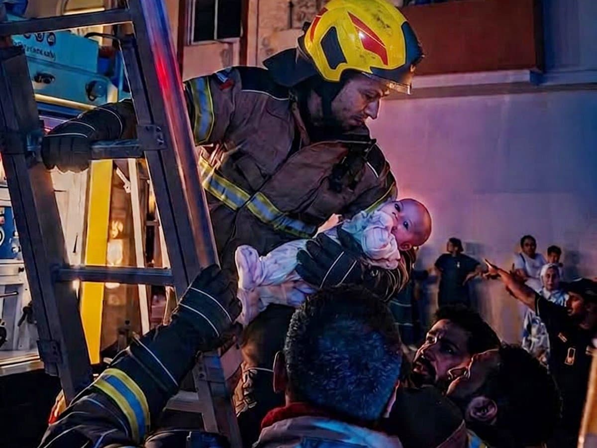 Emergency services rescuing a newborn from an apartment fire in Sharjah.