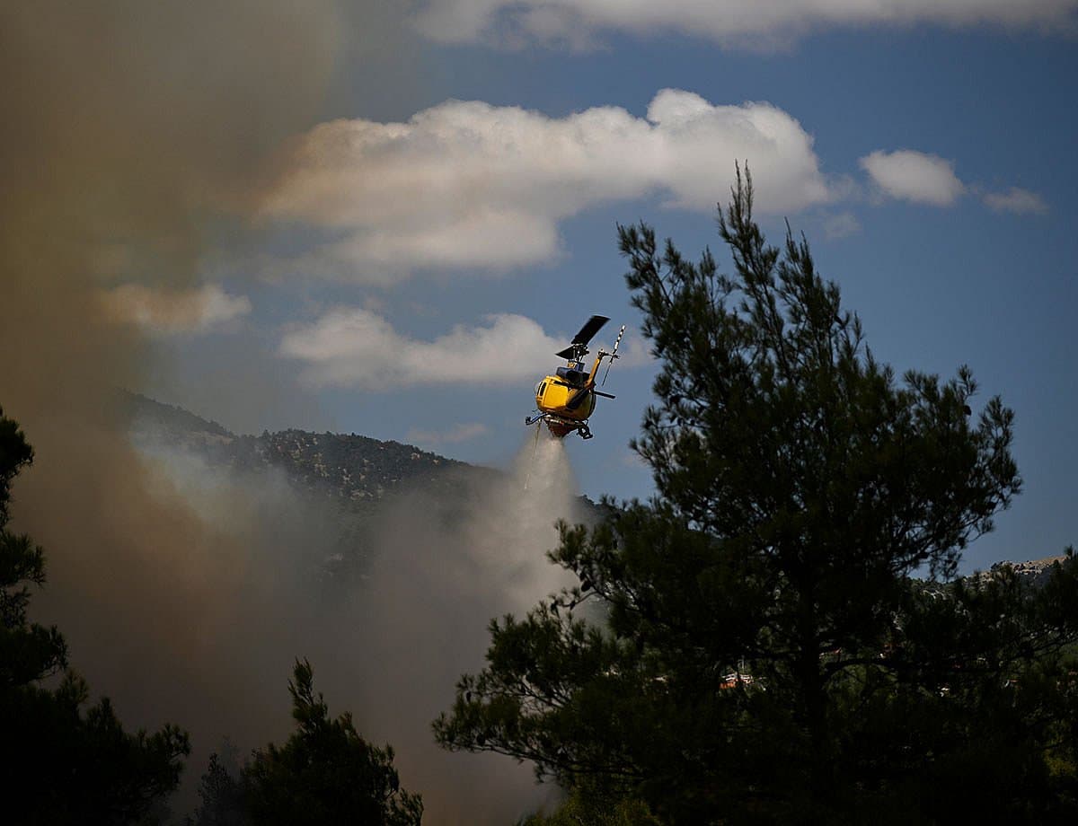 Aerial view of wildfires in Greece with firefighting helicopters in action.