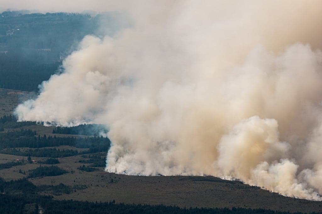 Aerial view of wildfires in Greece and Belgium with smoke and evacuations.