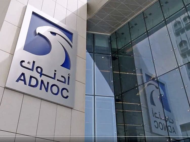ADNOC logo with oil barrels and market graphs in the background