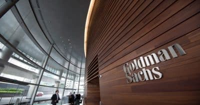 Goldman Sachs logo with a backdrop of financial market graphs