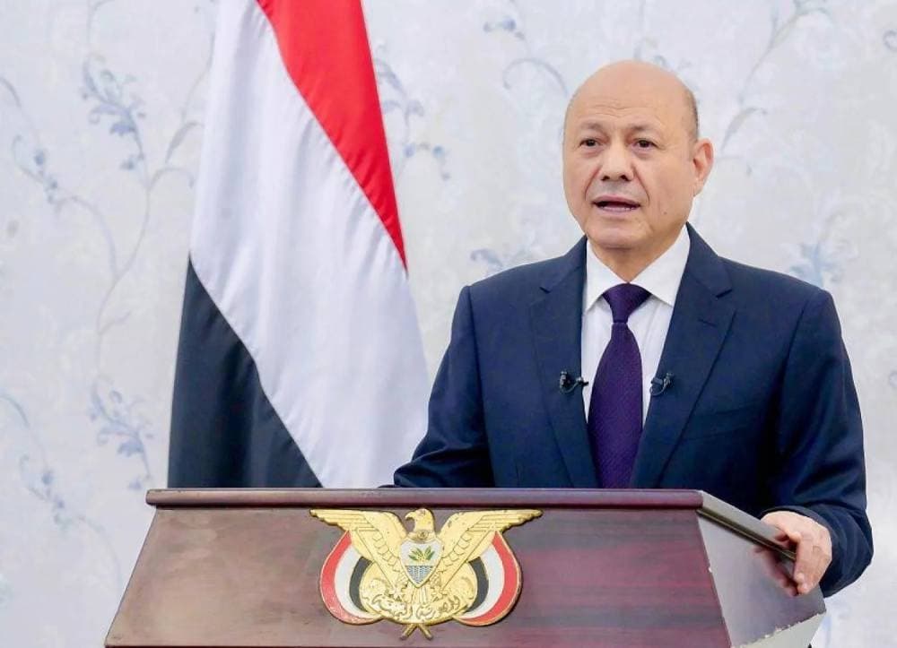 Rashad al-Alimi addressing the nation with Yemen's flag in the background during a military mobilization announcement.