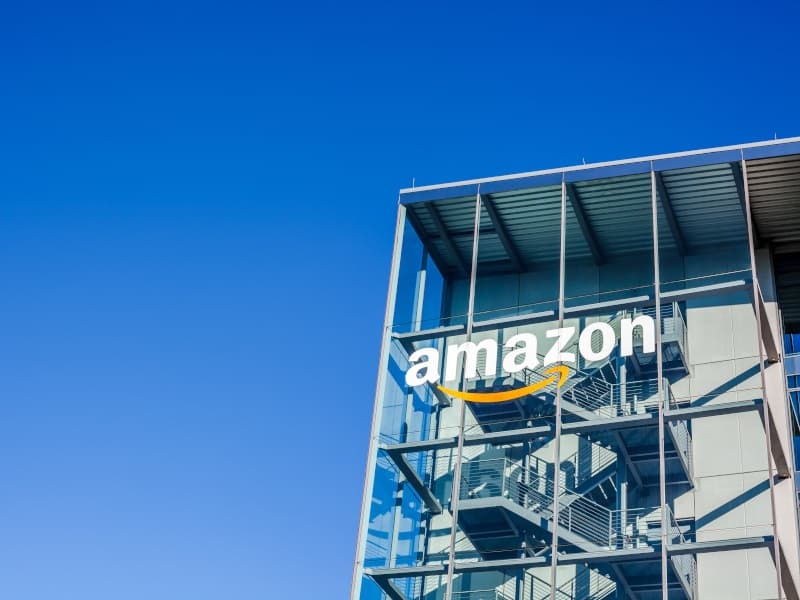 Amazon logo with a backdrop of digital cloud services and AI technology.