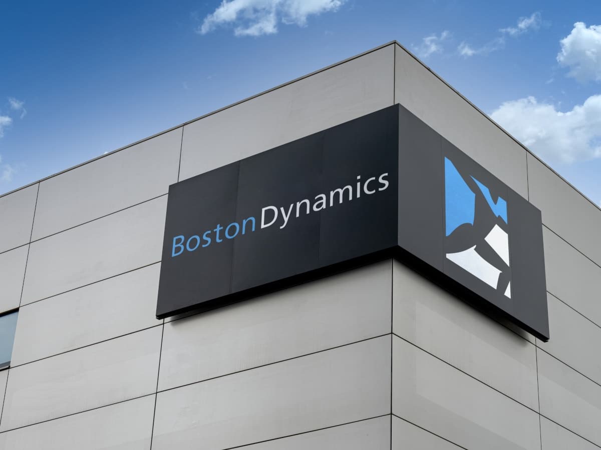 Rohit Prasad, new CEO of Boston Dynamics, with robotic technology in the background.