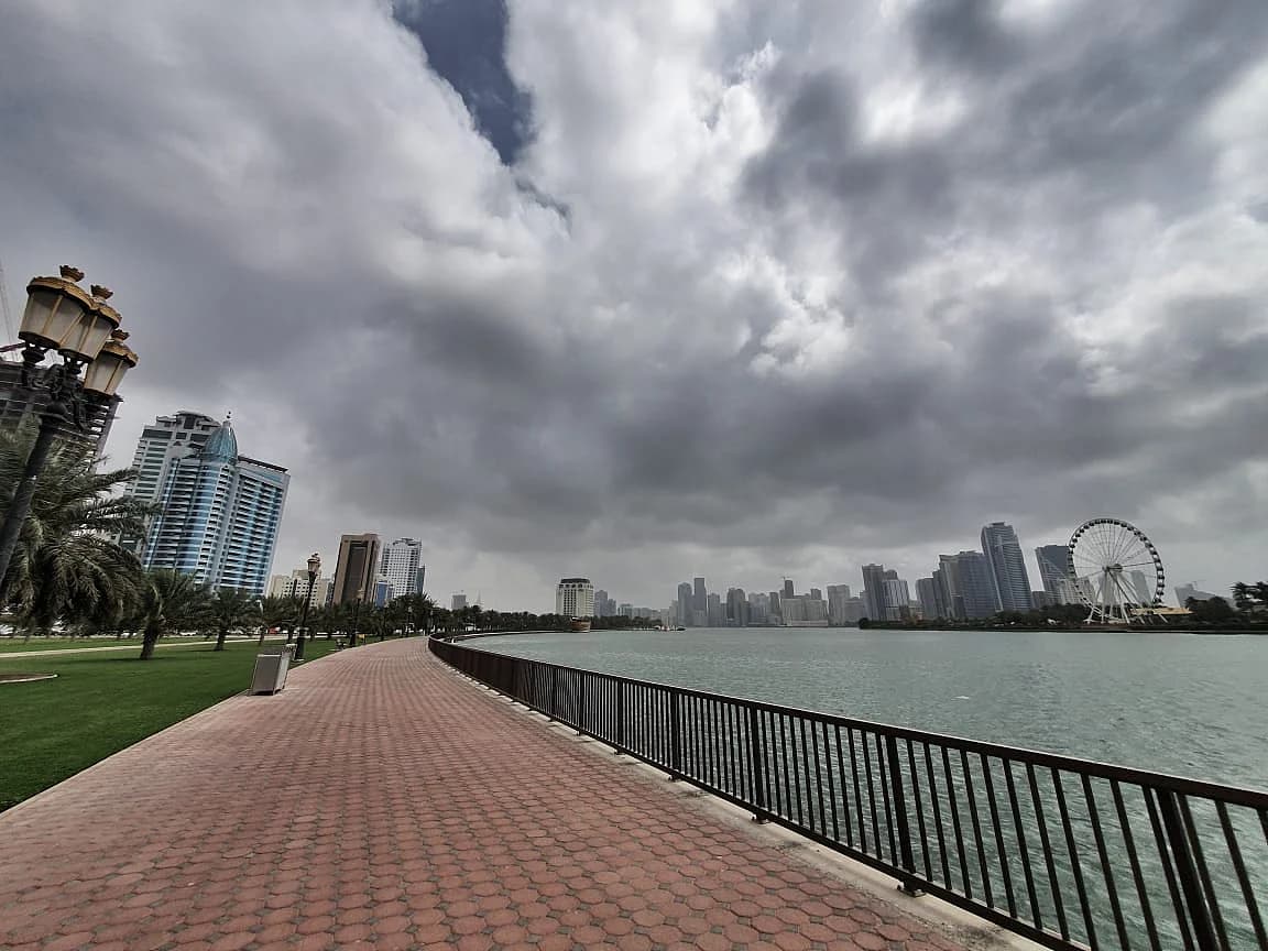Minimalist graphic of strong wind gusts and rain clouds over the UAE skyline with low road visibility