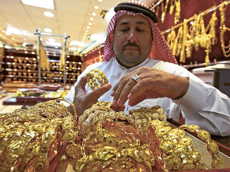 Gold bars with a backdrop of economic data charts and geopolitical maps.