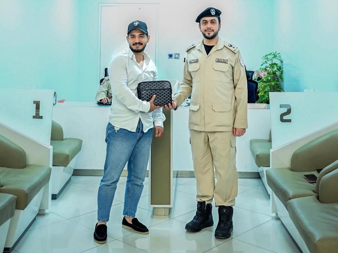 Sharjah Police officers returning a recovered bag to a resident.
