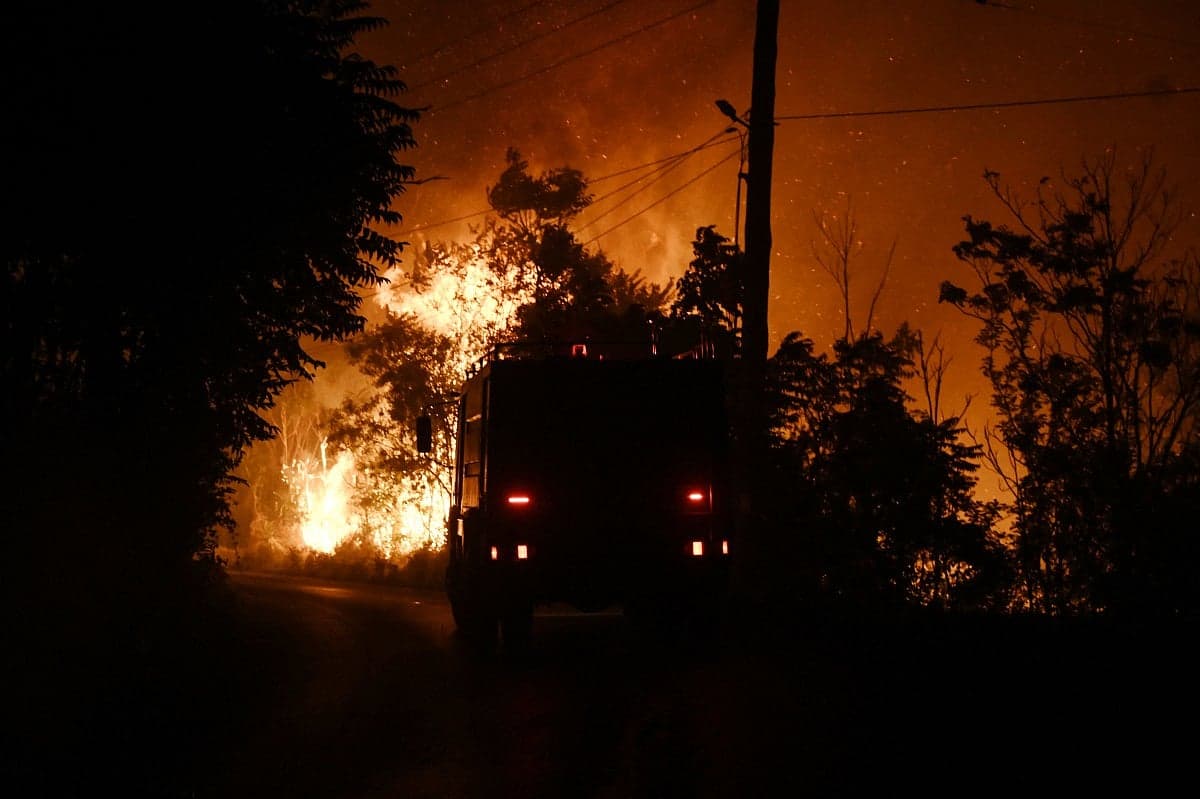Aerial view of wildfires raging through forests and homes in Greece.