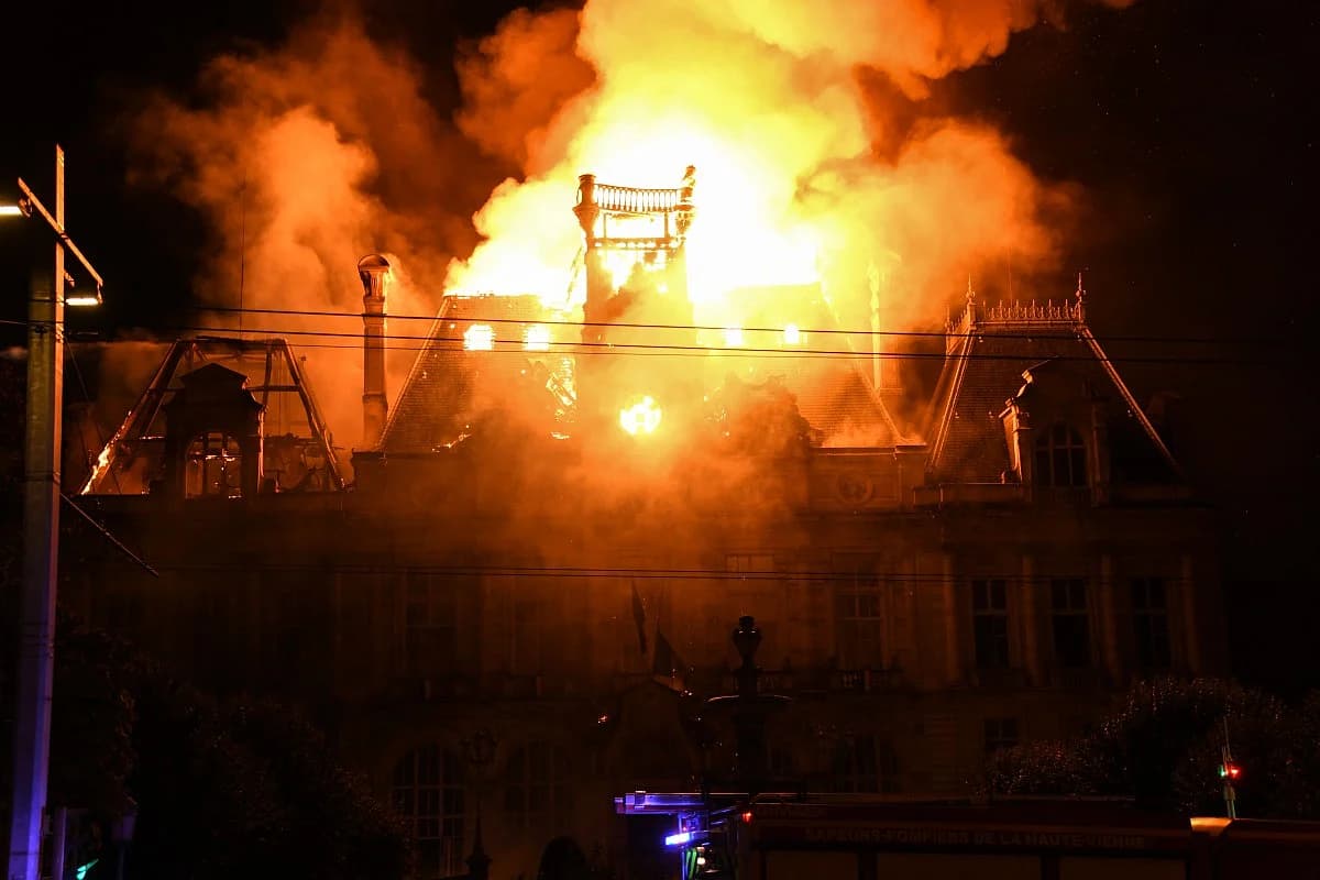 Protesters in France during unrest over rising living costs, with police and damaged businesses visible.