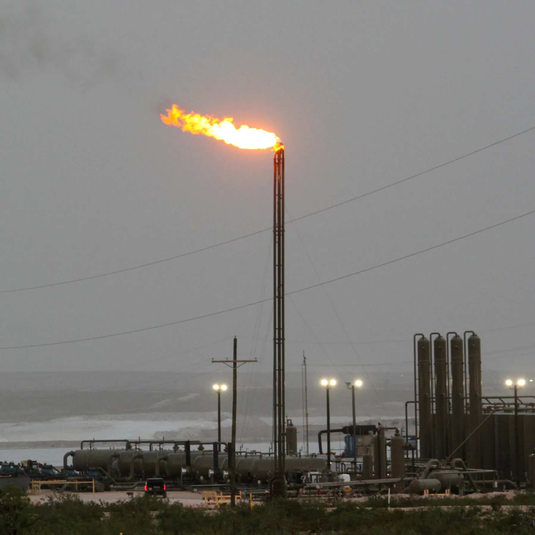 Industrial oil field pump jack operating in a rural field under a clear sky representing US methane emission standards deregulation